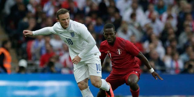 England's Wayne Rooney, left, competes for the ball with Peru's Luis Advincula during the international friendly soccer match between England and Peru at Wembley Stadium in London, Friday, May 30, 2014.  (AP Photo/Matt Dunham)