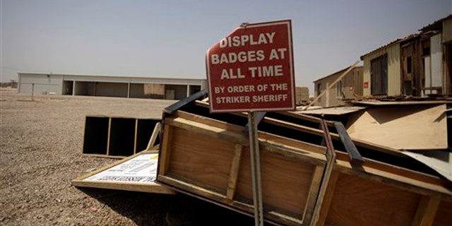 In this Aug. 4 photo, scraps of wood from the post office and a sign remain at a shuttered Camp Sather, part of the sprawling U.S. military Victory Base Complex that is set to close in Baghdad, Iraq.