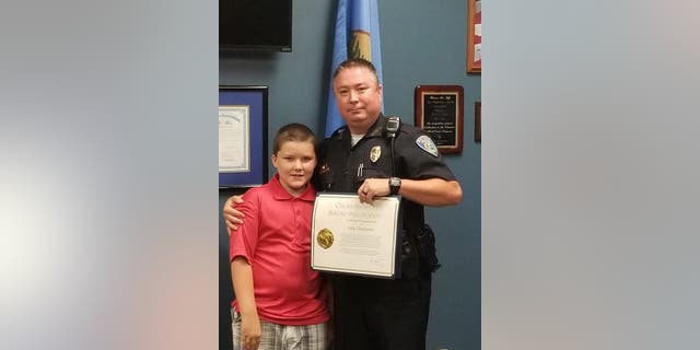 Officer Jody Thompson after receiving his certificate of commendation, posing with John.