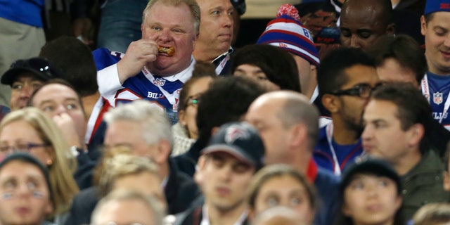 Toronto Mayor Rob Ford eats during the first half of an NFL football game between the Atlanta Falcons and the Buffalo Bills on Sunday, Dec. 1, 2013, in Toronto. (AP Photo/Gary Wiepert)