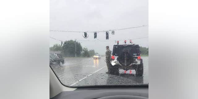 A soldier got out of his car to salute a funeral procession in the rain.