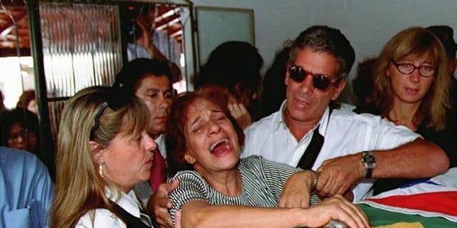 Lidia Pinto Machado, center, mother of Maria Isabel Monteiro Alves, mourns over her daughter's coffin during funeral services in 1995.