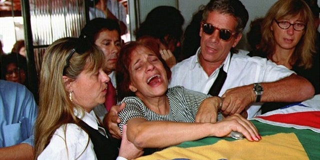 Lidia Pinto Machado, center, mother of Maria Isabel Monteiro Alves, mourns over her daughter's coffin during funeral services in 1995.