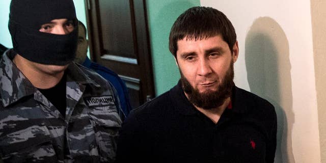 A police officer, left, escorts Zaur Dadaev, one of five suspects held in the killing of Russian opposition politician Boris Nemtsov, is escorted in a court in Moscow, Russia, Monday, Oct. 3, 2016. A Moscow military court is beginning to hear the case of five people accused of involvement in the killing of Nemtsov in February 2015. (AP Photo/Pavel Golovkin)