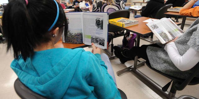 ** FOR USE MONDAY, Dec. 13 AND THEREAFTER** In this photo taken on Dec. 3, 2010, sophomore Ariel Russell follows along in her book as another student reads out loud in the John Jackson's U.S. history class at the Franklin High School in Franklin, Ind. School officials hope to give even more students a chance to earn college credits by making more dual-credit courses available. The goal is to get students who are planning to attend college a head start, as well as to give students the confidence that they can succeed in college level courses. (AP Photo/Daily Journal, Scott Roberson)