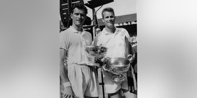 FILE - In this July, 6, 1957, file photo, winning doubles partners Budge Patty, left, and Gardnar Mulloy, both of the United States, hold their trophies after being presented by Queen Elizabeth at Wimbledon. Mulloy, a member of the International Tennis Hall of Fame who won 129 U.S. national titles, died Monday night, Nov. 14, 2016, in Miami. He was 102. (AP Photo/File)
