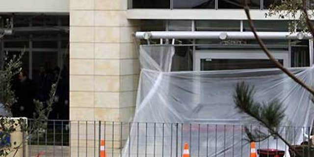 Feb. 18: Greek Police officers are seen, left, as a plastic sheet covers a parked car used in a foiled bomb attack at the Citibank offices in Athens.