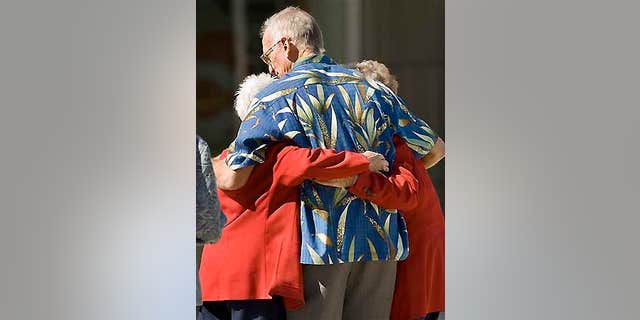 Two red-coated ushers at televangelist Robert H. Schuller's Crystal Catherdral get a hug after witnessing a man shoot himself in the church.