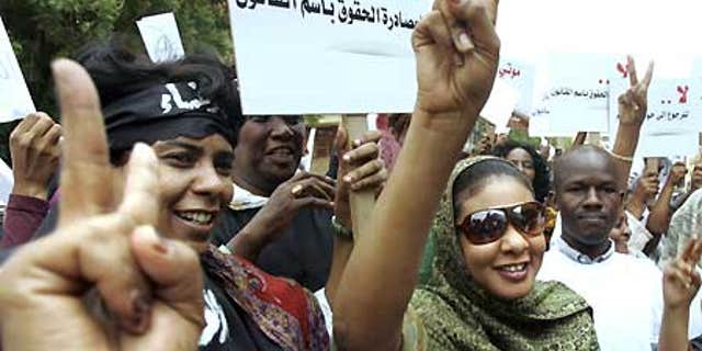 Aug. 4: Sudanese journalist Lubna Hussein, right, who faces 40 lashes on the charge of 'indecent dressing,' flashes a victory sign to her supporters.