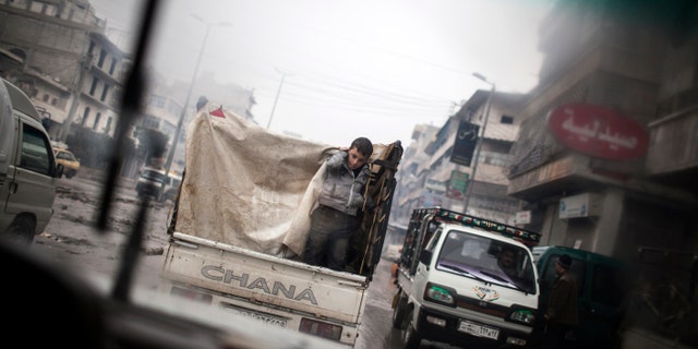 A boy is seen through a car window as he rides on the back of a truck in the streets of Aleppo, Syria, Saturday, Jan. 5, 2013. The revolt against President Bashar Assad that started in March 2011 began with peaceful protests but morphed into a civil war that has killed more than 60,000 people, according to a recent United Nations recent estimate. (AP Photo/ Andoni Lubaki)