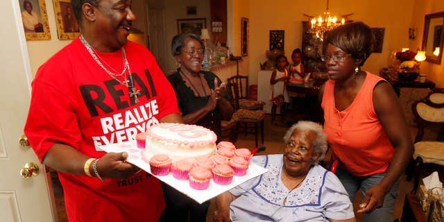 FILE- In this July 25, 2015, file photo, Terrance Jackson, left, Doris Ware, second from left, and Beverly Booker, right, sing "Happy Birthday To You" to Bernice Williams, seated, as she celebrates her 103rd birthday in the Mill City neighborhood of Dallas.