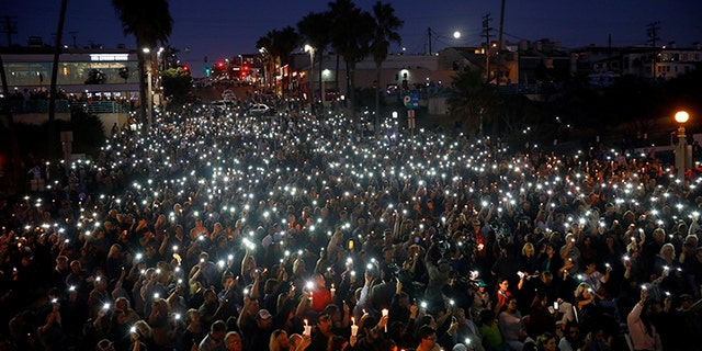 People hold candles and flashlights into the air during a memorial for Rachael Parker and Sandy Casey, Manhattan Beach city employees and victims of the October 1st Las Vegas Route 91 music festival mass shooting, in Manhattan Beach, California, U.S., October 4, 2017.