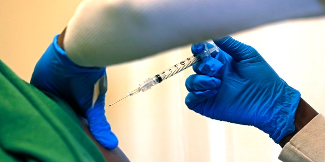 A registered nurse administers a flu shot to a patient.