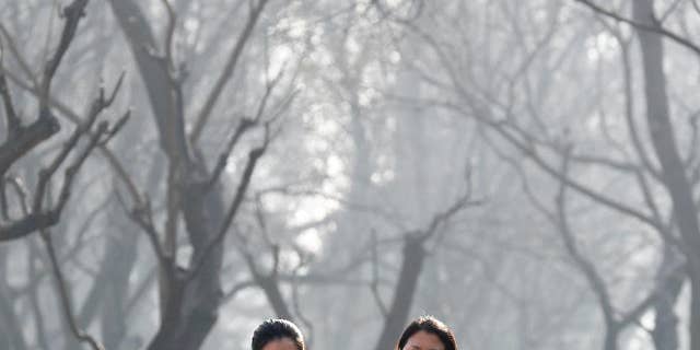 Chinese women wearing masks to protect themselves from air pollution walk through Ritan Park shrouded by dense smog in Beijing three years ago. (AP Photo/Andy Wong, File)
