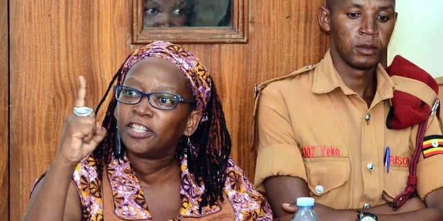In this photo taken on Monday April 10, 2017, Makerere University researcher Dr Stella Nyanzi, left, gestures in the dock at Buganda Road Court in the capital Kampala, Uganda. A Ugandan academic detained for calling the country's president "a pair of buttocks" resisted attempts to forcibly carry out psychiatric tests on her, her attorney said Thursday, April 13 describing the alleged incident as an attack on her dignity.(AP Photo)