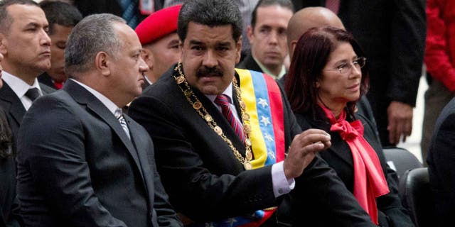 El presidente venezolano Nicolás Maduro, al centro, habla con Diosdado Cabello, presidente de la Asamblea Nacional, izquierda, durante una ceremonia para conmemorar el 185to aniversario de la muerte del héroe independentista Simón Bolivar en Caracas, Venezuela, el jueves 17 de diciembre de 2015. La mujer a la derecha es la primera dama Cilia Flores. (Foto AP/Fernando Llano)
