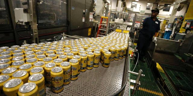 In this March 11, 2015 photo, newly-filled and sealed cans of Coors Banquet beer move along on a conveyor belt at the MillerCoors Brewery, in Golden, Colo. The Labor Department releases the Producer Price Index for March on Tuesday, April 14, 2015. (AP Photo/Brennan Linsley)