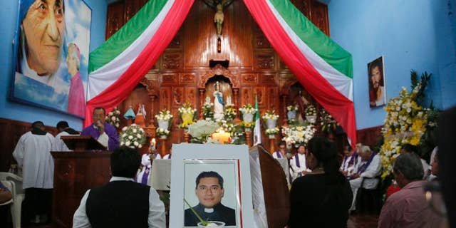 FILE - In this Sept. 21, 2016 file photo, people gather at Our Lady of Asuncion Church in Paso Blanco, Veracruz state, Mexico, for the funeral Mass of Rev. Jose Alfredo Suarez de la Cruz, one of two priests who was found bound and shot to death along a roadside on Sept. 19. Mexican authorities arrested a suspect in the abduction and murder of the two priests in Veracruz state last month. Mexico City prosecutors say in a statement released Monday, Oct. 17, 2016, that the unidentified person was detained Oct. 13 along with another person after they allegedly car-jacked a couple in the capital. (AP Photo/Marco Ugarte, File)