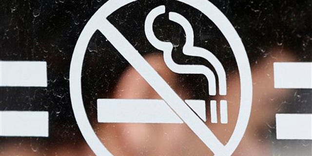 A student waits for a bus behind a no smoking sign at the State University of New York at Albany in Albany, N.Y., on Tuesday, June 26, 2012. Tobacco use bans are sweeping campuses nationwide. (AP Photo/Mike Groll)