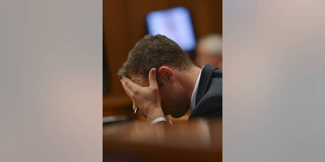 March 12, 2014: Oscar Pistorius cradles his head in his hands as he listens to cross questioning about the events surrounding the shooting death of his girlfriend Reeva Steenkamp, in court during the second week of his trial in Pretoria, South Africa.
