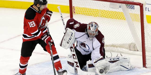 Colorado Avalanche goalie Semyon Varlamov, right, of Russia, gloves the puck as New Jersey Devils right wing Steve Bernier (18) looks for a rebound during the third period of an NHL hockey game, Saturday, Nov. 15, 2014, in Newark, N.J. The Avalanche won 3-2. (AP Photo/Julio Cortez)