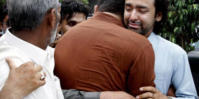 In this May 2013 file photo, people comfort Musa Gilani, right, the brother of Ali Haider Gilani who was kidnapped in Multan, Pakistan.