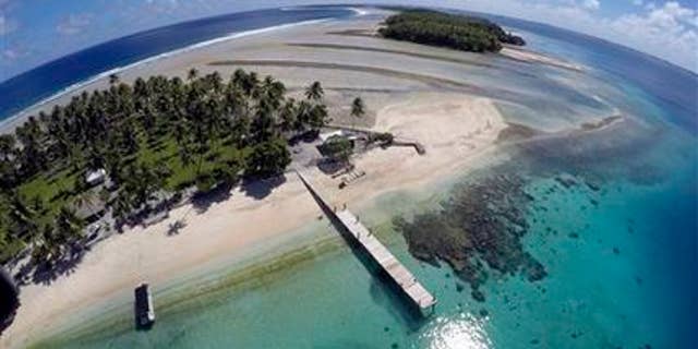 This Nov. 8, 2015 aerial photo shows a small section of the atoll that has slipped beneath the water line only showing a small pile of rocks at low tide on Majuro Atoll in the Marshall Islands. Climate change poses an existential threat to places like the Marshall Islands, which protrude only 6 feet (2 meters) above sea level in most places. (AP Photo/Rob Griffith)