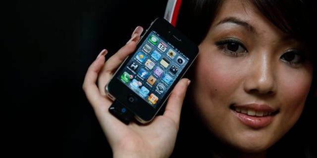 A model holds the latest iPhone 4 (with an attached Bluetooth device) during a promotional event in Hong Kong Thursday July 15, 2010.
