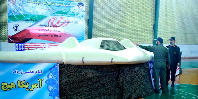 Dec. 8, 2011: A photo by the Iranian Revolutionary Guards purportedly shows a U.S. RQ-170 Sentinel drone that Tehran says its forces downed earlier in the week, as the chief of the aerospace division of Iran's Revolutionary Guards, Gen. Amir Ali Hajizadeh, right, listens to an unidentified colonel.