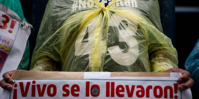 FILE - In this May 26, 2016, file photo, a relative carries signs that reads in Spanish "They took them alive!" referring to the 43 missing students from a rural teachers college during a march in Mexico City, Thursday. Mexico's National Human Rights Commission said Monday, July 11, that a classmate of 43 college students who disappeared in 2014 had been tortured before his body was found the following day. (AP Photo/Eduardo Verdugo, File)