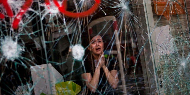 FILE - In this March 29, 2012 file photo, Mireia Arnau, 39, reacts behind the broken glass of her shop stormed by demonstrators during clashes with the police at the general strike in Barcelona. In a statement released Friday April 19, 2013, this photo by Associated Press photographer Emilio Morenatti won the Ortega y Gasset award by Spain’s leading newspaper El Pais, saying Morenatti captures "terrible emotion” in the store worker terrified at the damage caused by a violent street protest, “By observing it one feels the fear of the clerk,” the jury says. (AP Photo/Emilio Morenatti, File)