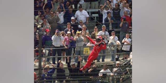 FILE - In this May 27, 2001, file photo, Helio Castroneves, of Brazil, celebrates after winning the 85th running of the Indianapolis 500 auto race by climbing the fencing near the start-finish line at Indianapolis Motor Speedway. (AP Photo/Dave Parker, File)