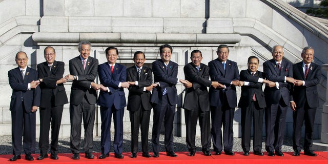 Japanese Prime Minister Shinzo Abe, center, and leaders of ASEAN countries join hands for a photo session of Japan-ASEAN commemorative summit at Akasaka State Guesthouse in Tokyo, Japan, Saturday, Dec. 14, 2013. 