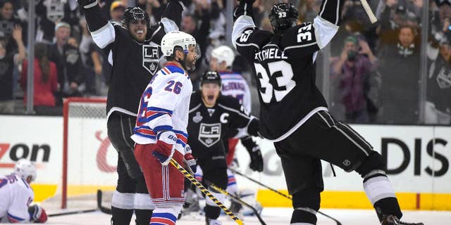 Los Angeles Kings right wing Dustin Brown, center, celebrates after scoring the game-winning goal, along with center Anze Kopitar, second from left, of Slovenia, and defenseman Willie Mitchell, right, as New York Rangers center Brad Richards, left, lies on the ice and Martin St. Louis (26) watches during the second overtime period in Game 2 of the NHL hockey Stanley Cup Finals, Saturday, June 7, 2014, in Los Angeles. The Kings won 5-4. (AP Photo/Mark J. Terrill)