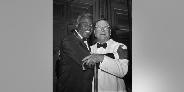 FILE - In this July 20, 1962 file photo, baseball player Jackie Robinson embraces Branch Rickey in New York. Rickey was general manager of the Brooklyn Dodgers when Robinson was hired. The home area of the late baseball executive Rickey expects increased interest in his southern Ohio roots from his depiction in the movie “42,” in which Harrison Ford plays the man who signed Jackie Robinson to challenge baseball’s color line. (AP Photo/File)