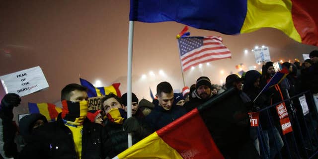 Protesters wave U.S., German and Romanian flags during a protest in Bucharest, Romania, Monday, Feb. 6, 2017. The leader of Romania's ruling center-left coalition said Monday the government won't resign following the biggest demonstrations since the end of communism against a measure that would ease up on corruption. (AP Photo/Darko Bandic)
