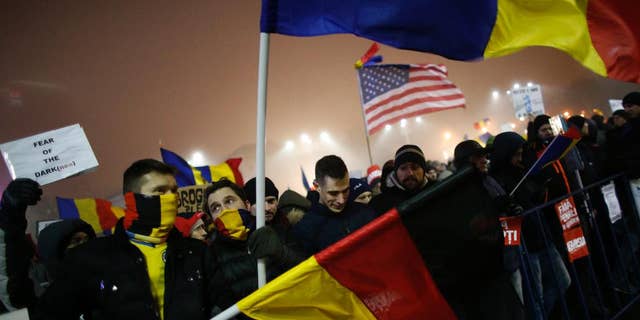 Protesters wave U.S., German and Romanian flags during a protest in Bucharest, Romania, Monday, Feb. 6, 2017. The leader of Romania's ruling center-left coalition said Monday the government won't resign following the biggest demonstrations since the end of communism against a measure that would ease up on corruption. (AP Photo/Darko Bandic)