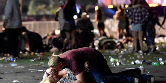A man lays on top of a woman as others flee the Route 91 Harvest country music festival grounds in October 2017.