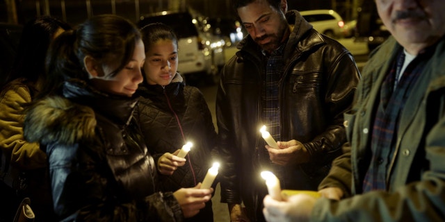 People light candles with members of Rafael Ramos' family in Brooklyn, New York, Sunday, Dec. 21, 2014.