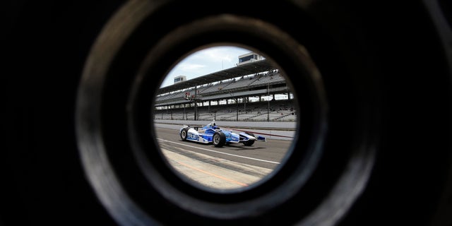 The car driven by Sebastian Saavedra, of Colombia, is seen through a wheel as its pulled through the pit area during practice for the Indianapolis 500 auto race at the Indianapolis Motor Speedway in Indianapolis, Wednesday, May 15, 2013. (AP Photo/Darron Cummings)