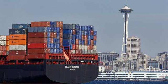 FILE - In this Feb. 15, 2015 file photo, the Space Needle towers in the background beyond a container ship anchored in Elliott Bay near downtown Seattle. The Commerce Department releases international trade data for January on Friday, March 6, 2015. (AP Photo/Elaine Thompson, File)