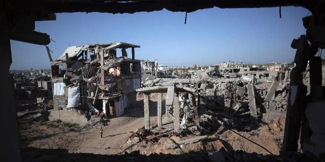 File - In this March 30, 2015 file photo, a Palestinian girl walks next to destroyed houses, in the Shijaiyah neighborhood of Gaza City. The International Monetary Fund said in a Tuesday, May, 19, 2015 report, that reconstruction of the Gaza Strip is going “far more slowly than expected” after a devastating war between Israel and the Hamas militant group last year. The IMF said that just over a quarter of $3.5 billion pledged for reconstruction has been disbursed and urged donors to fulfill their pledges. (AP Photo/Khalil Hamra, File)