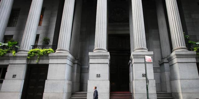 In this Wednesday, Oct. 8, 2014 photo, a man walks to work on Wall Street, in New York. European shares were higher Monday, Nov. 10, 2014, supported by expectations the European Central Bank is prepared to offer new stimulus to nurse the region's recovery. Gains in Asia were spurred by approval of a cross-border trading link between Hong Kong and Shanghai that will give foreigners greater access to Chinese shares. Wall Street looked poised to edge higher. (AP Photo/Mark Lennihan)