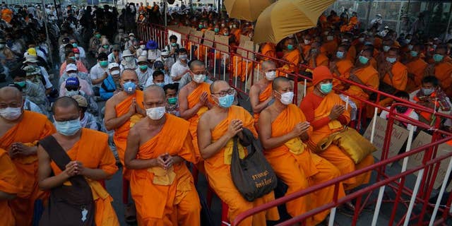 Buddhist monks of the Dhammakaya sect sit anticipating police raid outside the Dhammakaya sect temple in Pathum Thani, north of Bangkok, Thailand. Four Thai Buddhist monks have been sent to rehab after testing positive for methamphetamine, according to reports. 