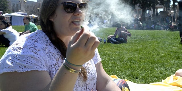 A woman exhales marijuana smoke during the 4/20 Rally at the Civic Center in Denver, Colorado, April 20, 2014. REUTERS/Mark Leffingwell
