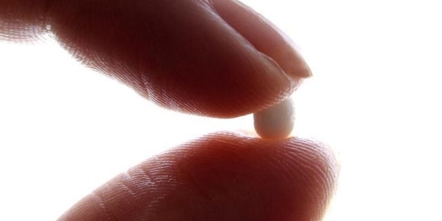 An illustration picture shows a woman holding a birth control pill at her home in Nice January 3, 2013. REUTERS/Eric Gaillard