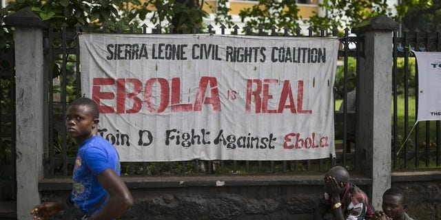 A man walks past a banner about Ebola in Freetown, Sierra Leone, December 16, 2014.