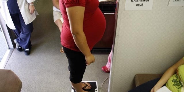 A pregnant woman stands on a scale before receiving a prenatal exam at the Maternity Outreach Mobile in Phoenix, Arizona October 8, 2009. REUTERS/Joshua Lott
