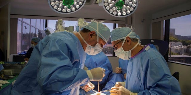 Doctors David Ghozland and Marc Winter make an incision in the belly button of a 49-year-old woman, Sheryl, who had two fibroids, in preparation for a single-site robotic-assisted hysterectomy at miVIP Surgery Center, in Los Angeles, California April 23, 2014. REUTERS/Lucy Nicholson