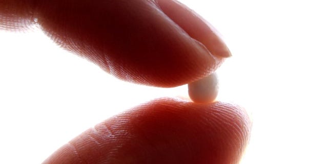 An illustration picture shows a woman holding a birth control pill at her home in Texas.